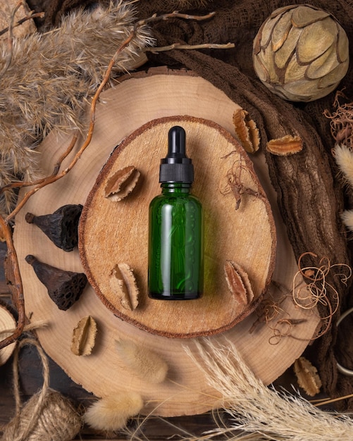 Dropper bottle on wood near natural boho decorations top view Cosmetic packaging Mockup