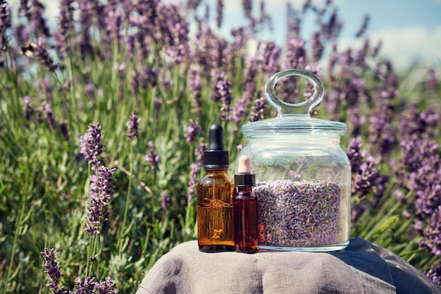 Dropper bottles of lavender essential oil glass jar of dry\
lavender flowers for making herbal tea