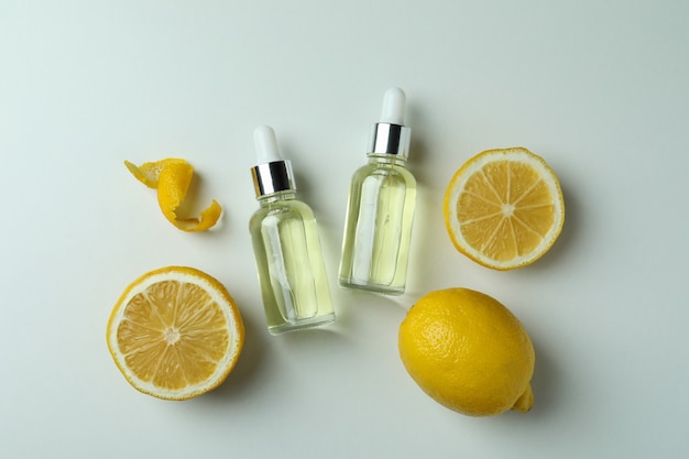 Bottiglie contagocce con olio e limoni su sfondo bianco isolato