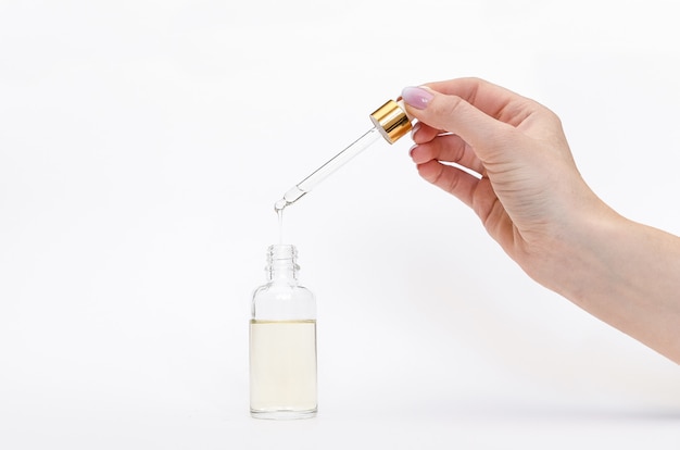 Dropper glass Bottle Mock-Up. Oily drop falls from cosmetic pipette on white background