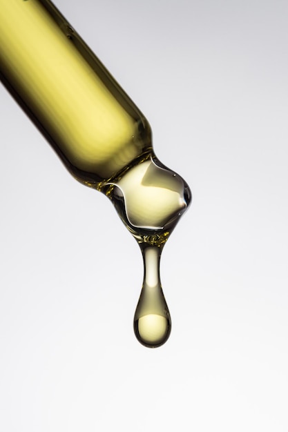 写真 白い背景に透明な黄色の滴と泡を持つスポイト ピペット抽象的な血清油酸化粧品