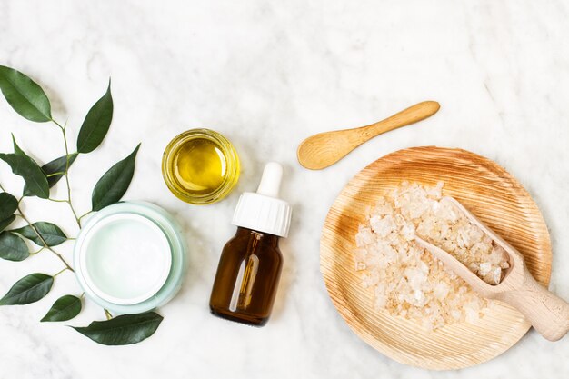 A dropper of skin oil and a moisturizer cream on a marble table in a top view