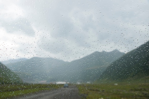 Gocce sul vetro dell'auto e sullo sfondo del paesaggio di montagna