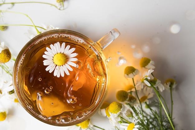 Drops of chamomile tea fall into a transparent mug in the sunlight