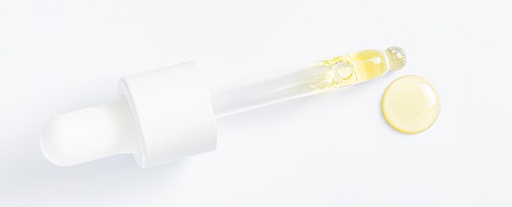 Drops of cosmetic serum and a pipette A skin care product White background Copy space