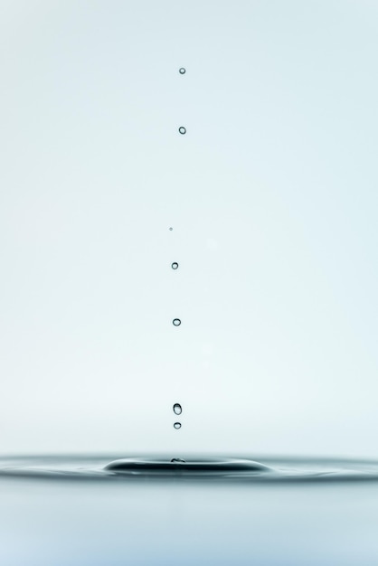 白い背景で水に落ちる滴