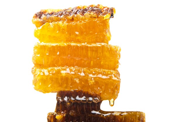 Drops of fresh honey dripping from a pyramid of wax honey. vitamin nutrition and bee product.