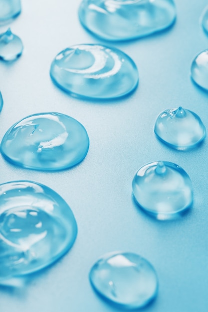 Drops of Gel with hyaluronic acid in the form of a smear of glossy texture on a blue surface