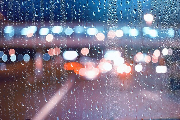 drops on glass auto road rain autumn night / abstract autumn background in the city, auto traffic, romantic trip by car