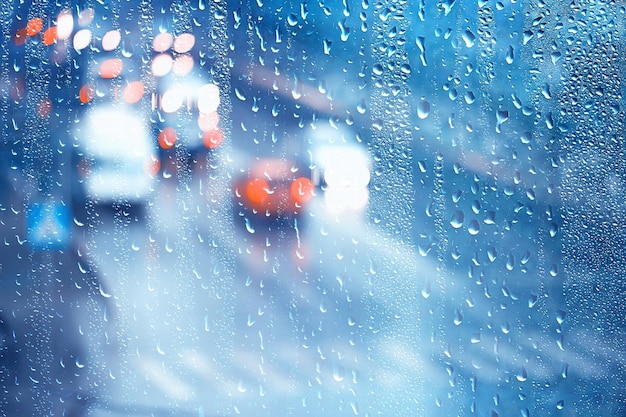 drops on glass auto road rain autumn night / abstract autumn background in the city, auto traffic, romantic trip by car