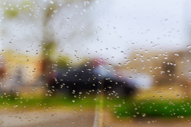 Drops Of Rain On Blue Glass Background. Street Bokeh Lights Out Of Focus.