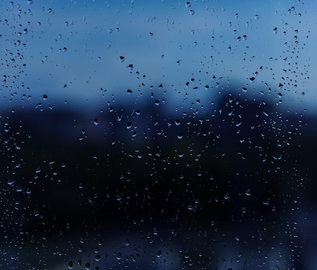 Gocce di pioggia su vetro blu. giorno di pioggia