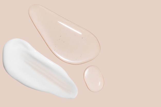 Drops of transparent gel and a dab of white cosmetic cream On a beige background