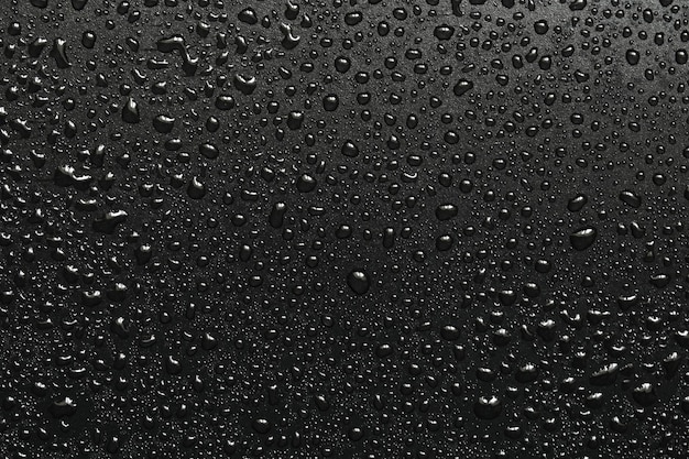 Photo drops of water on a black surface the condensate top view free space