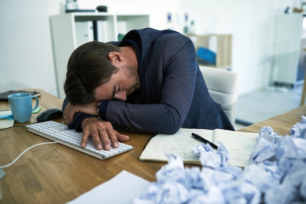 Photo drowning in paperwork shot of a stressed out businessman passed out at his desk overwhelmed by paperwork