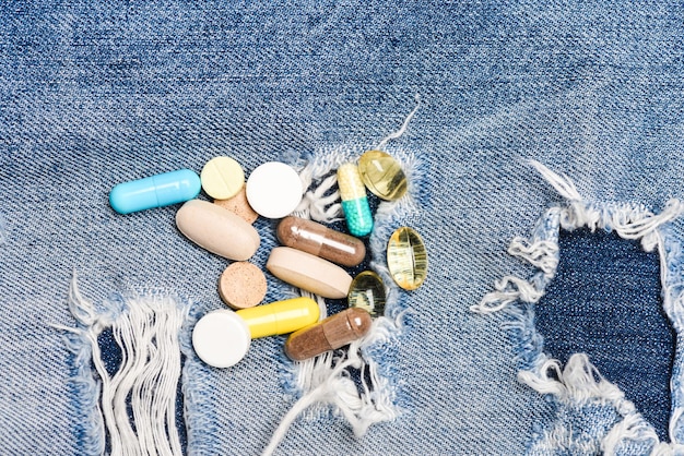 Drug addiction Medicine and treatment concept Drugs on denim background Set of colorful pills Mixing medicines Fast treatment Medicine prescription Health care and illness Dose and addiction