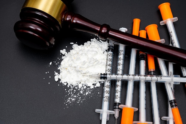 白い粉と黒い背景に使い捨て注射器の薬物犯罪の概念
