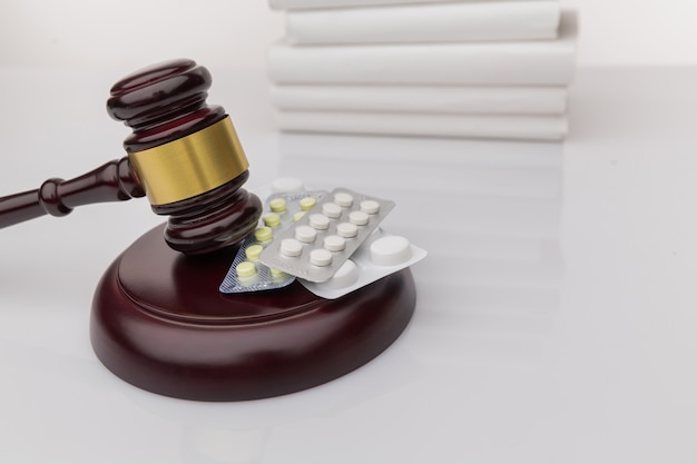 Наркотики и закон. судейский молоток и красочные таблетки на деревянном столе