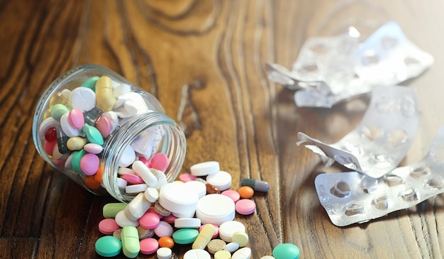 Drugs and coins in a glass jar on a wooden floor. Pocket savings from coins in a bank for medical services. Piggy bank in a glass jar with coins.