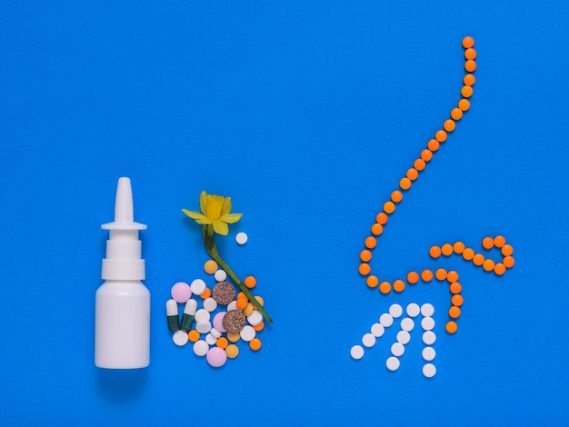 Drugs for the treatment of diseases of the nose and nose tablets on a blue background. Allergic to spring flowers. The concept of treatment of diseases of the nose and allergies. Flat lay.