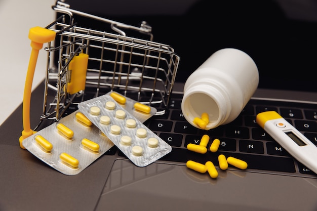 Drugs in trolley and medical tools on laptop, concept of online shopping.