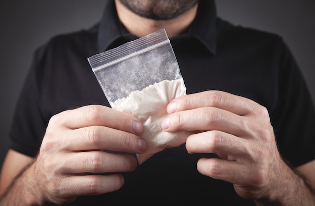 Drugsdealer die plastic pakketcocaïne vasthoudt.