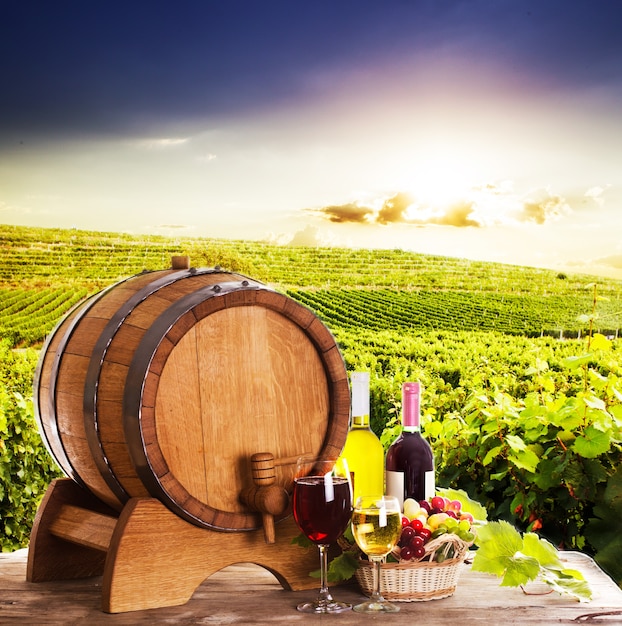 Druiven en flessen wijn in de buurt van het houten vat. Glazen wijn op tafel, concept van wijnmakerij - rood en wit