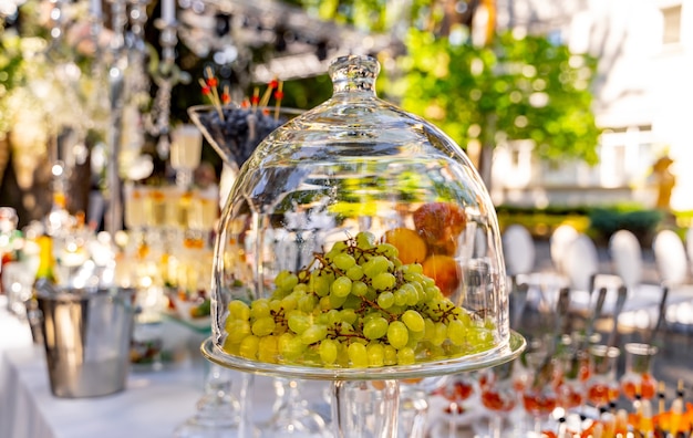 Druiven onder glas transparante koepel deksel. dessert op de feestelijke tafel. bruiloft tafeldecoratie. selectieve aandacht.