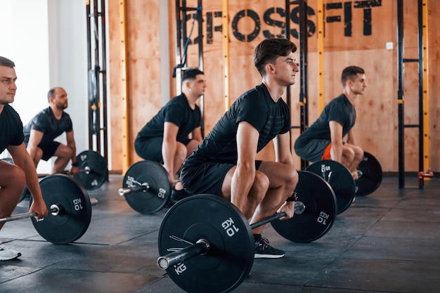 Druk bezig met oefeningen Groep jonge sportieve mensen hebben crossfitdag binnenshuis in de sportschool