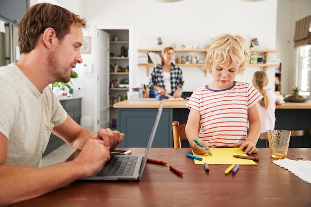 Foto drukke familie keuken vader en zoon werken aan tafel close-up