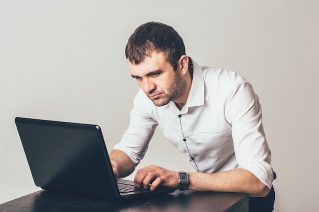 Drukke man werkt op de laptop op kantoor. De zakenman is gericht op het oplossen van de taken