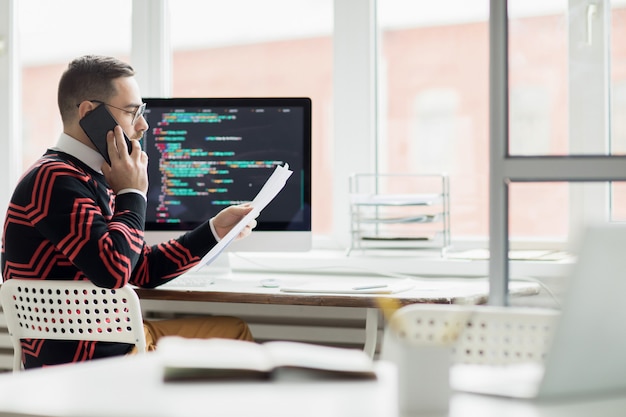 Drukke programmeur praten met de klant via de telefoon