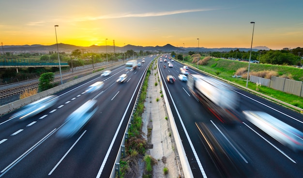 Foto drukke snelweg bij zonsondergang, voertuigen komen en gaan, stad stress