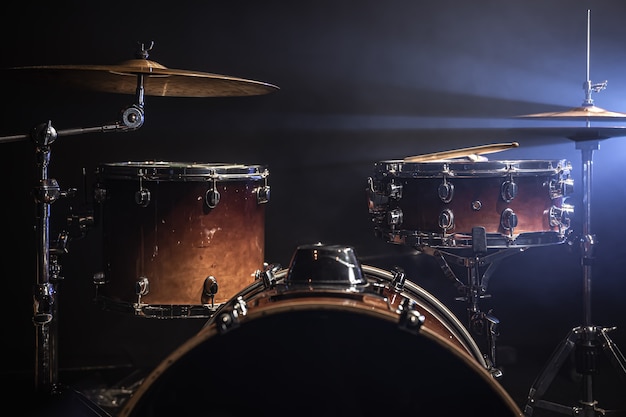 Drum kit on a dark background with stage lighting, copy space.