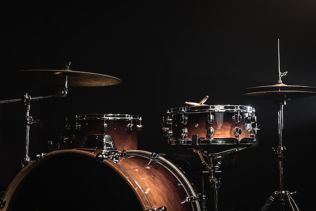 Drum kit on a dark background with stage lighting, copy space.