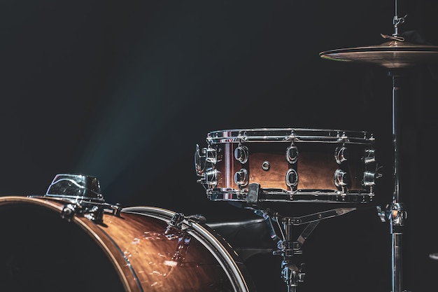 Drum set in a dark room with beautiful lighting, snare drum, cymbals, bass drum.