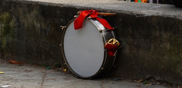 Foto un tamburo legato con un panno rosso sul pavimento di cemento