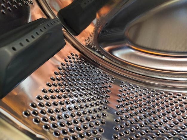 내부에서 본 세탁기의 드럼 구멍과 돌출부가 있는 반짝이는 금속 탱크 스테인리스 강판으로 만들어진 구멍이 있는 스테인리스 스틸 표면 세탁기의 내부 모습