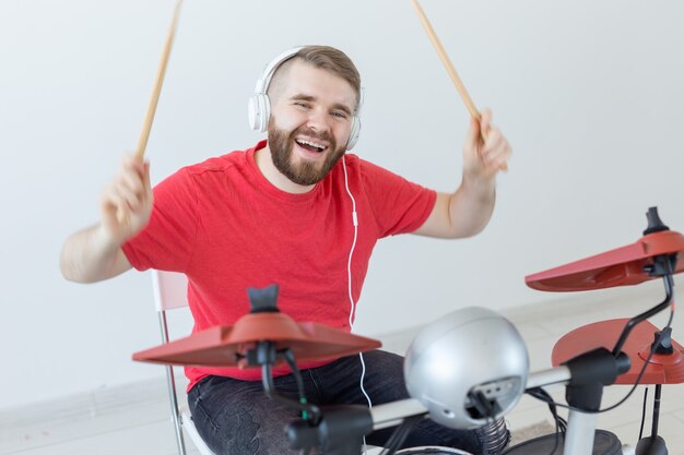 Drummer, hobby's en muziek concept - jonge man drummer in rood shirt die de elektronische drums speelt.