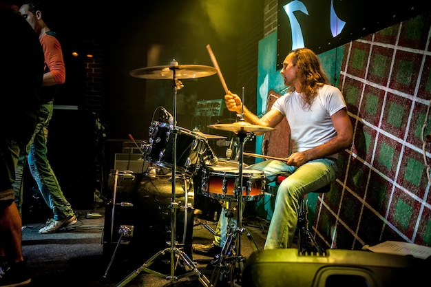 Drummer playing on drum set on stage. Warning - authentic shooting with high iso in challenging lighting conditions. A little bit grain and blurred motion effects.