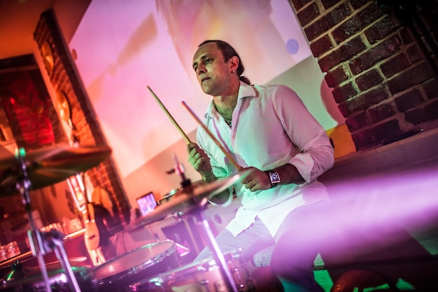 Drummer playing on drum set on stage. Warning - authentic shooting with high iso in challenging lighting conditions. A little bit grain and blurred motion effects.