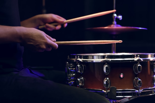 Drummer playing drum sticks on a snare drum in dark. Concert and live performance concept.