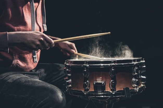 The drummer plays with mallets on floor tom in dark room