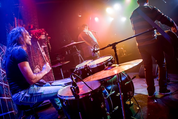 Foto drummer spelen op drumstel op het podium. authentiek fotograferen met hoge iso in uitdagende lichtomstandigheden. een beetje graan en wazige bewegingseffecten.