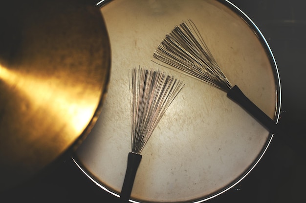 Drumsticks brushes resting on the snare drum