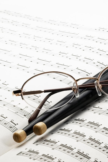 Photo drumsticks and eyeglasses on sheet music