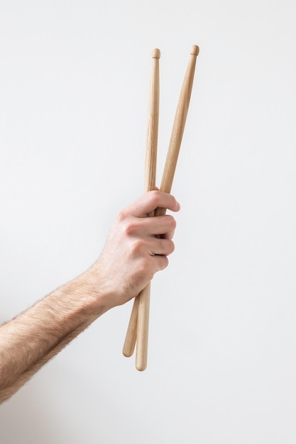Foto bastoncini di tamburo in mano di un uomo su uno sfondo bianco