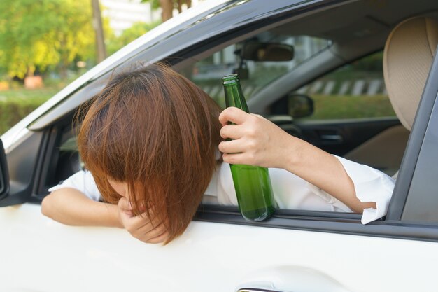 酔っているアジアの女性はあまり飲んでアルコールと運転中の車の後にめまいを感じる