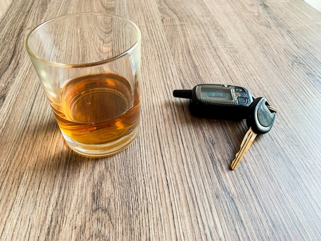 Drunk driving concept. Glass with whiskey and car key on the table.