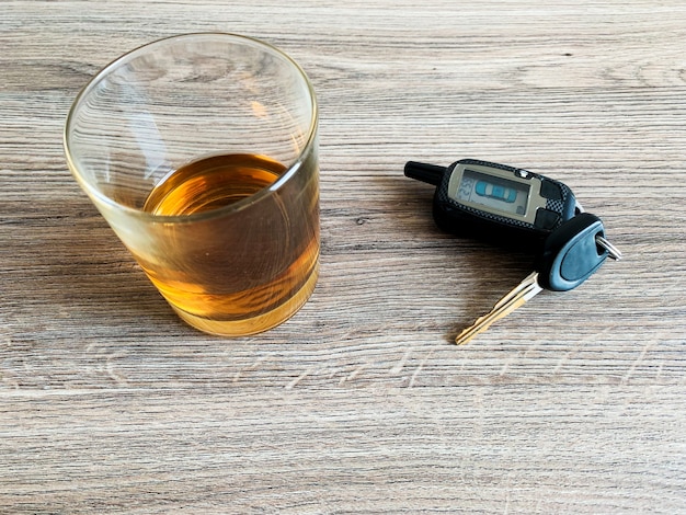 Drunk driving concept. Glass with whiskey and car key on the table.